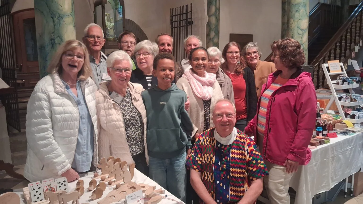 Gruppe beim Jubiläum des Eine-Welt-Kreises Günne vor einem Stand mit Selbstgemachtem in der Kirche.