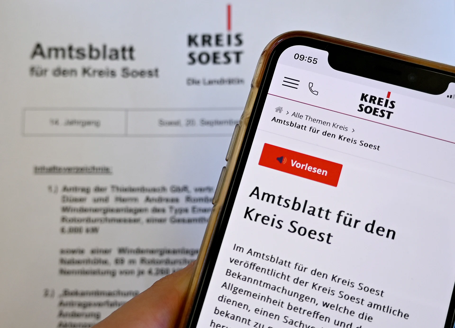 Ein Smartphone zeigt die Amtsblatt-Seite des Kreises Soest vor einer gedruckten Ausgabe.